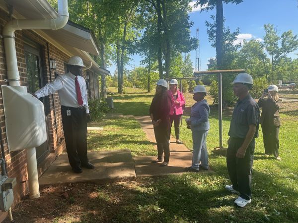 Group of people in hardhats looking at a residential unit outside. 