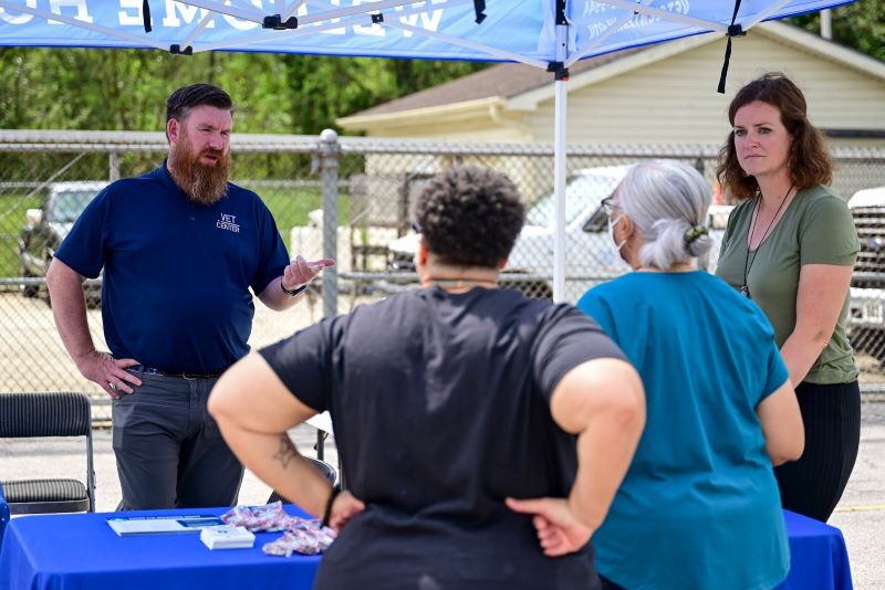 Man talking to attendees of the event booth. 