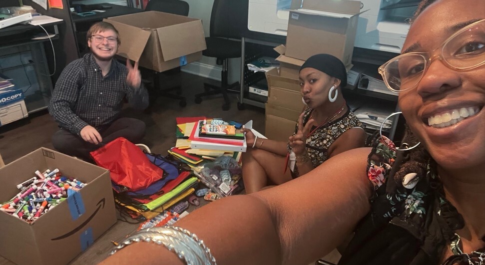 People sorting school supplies and posing for this photo. 